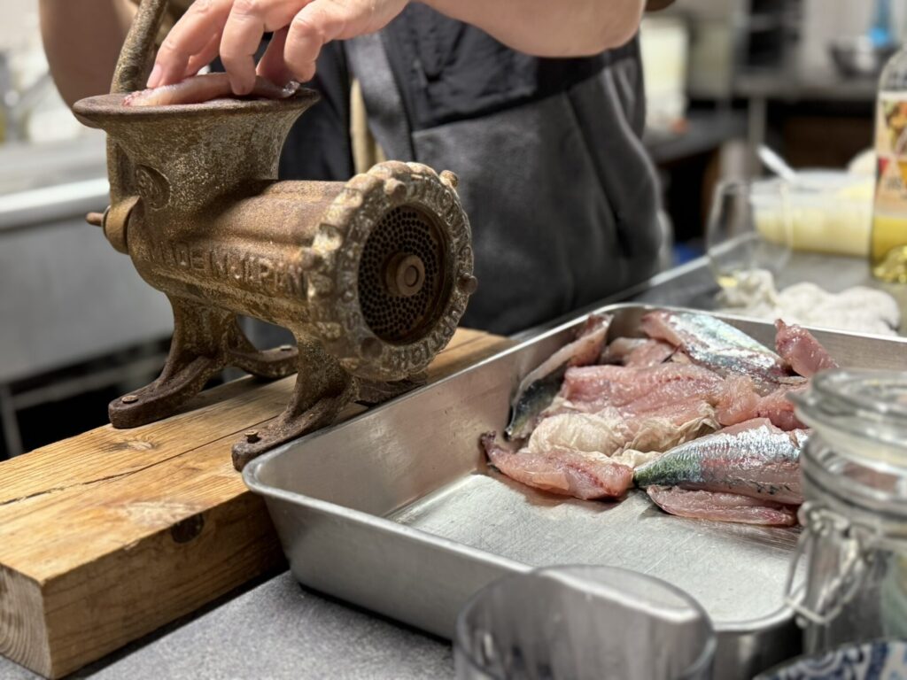 式根島の伝統料理「たたき」作りに使われる年代物の肉すり機で青ムロをミンチにする様子