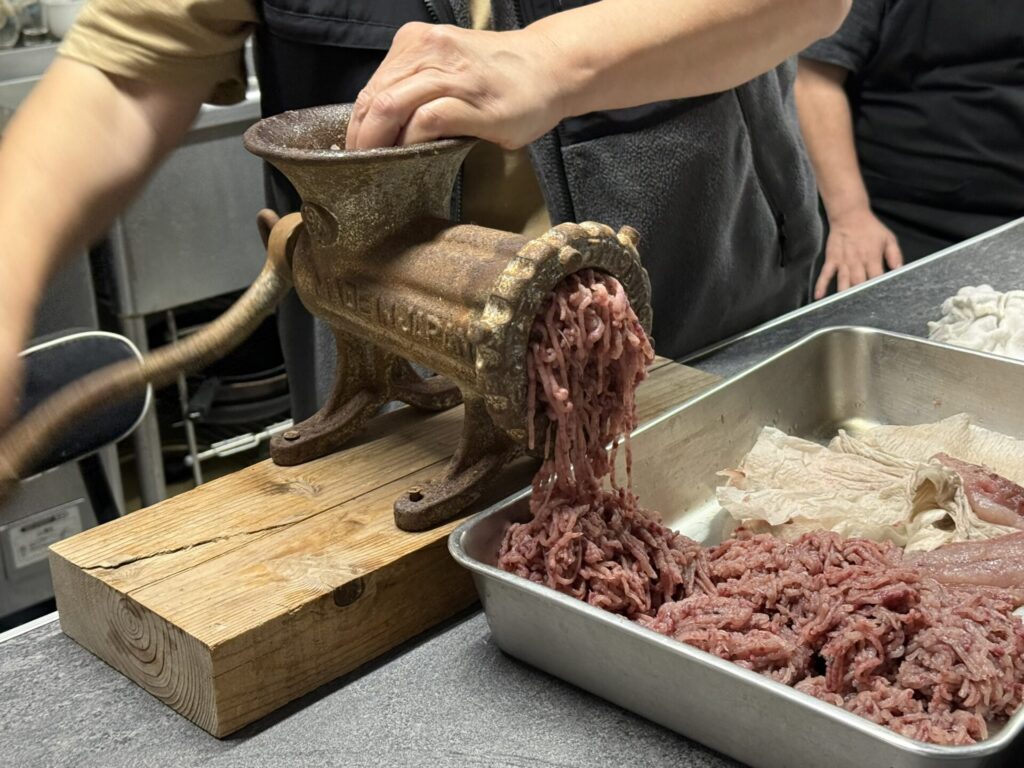 式根島の伝統料理「たたき」作りに使われる年代物の肉すり機で青ムロをミンチにする様子