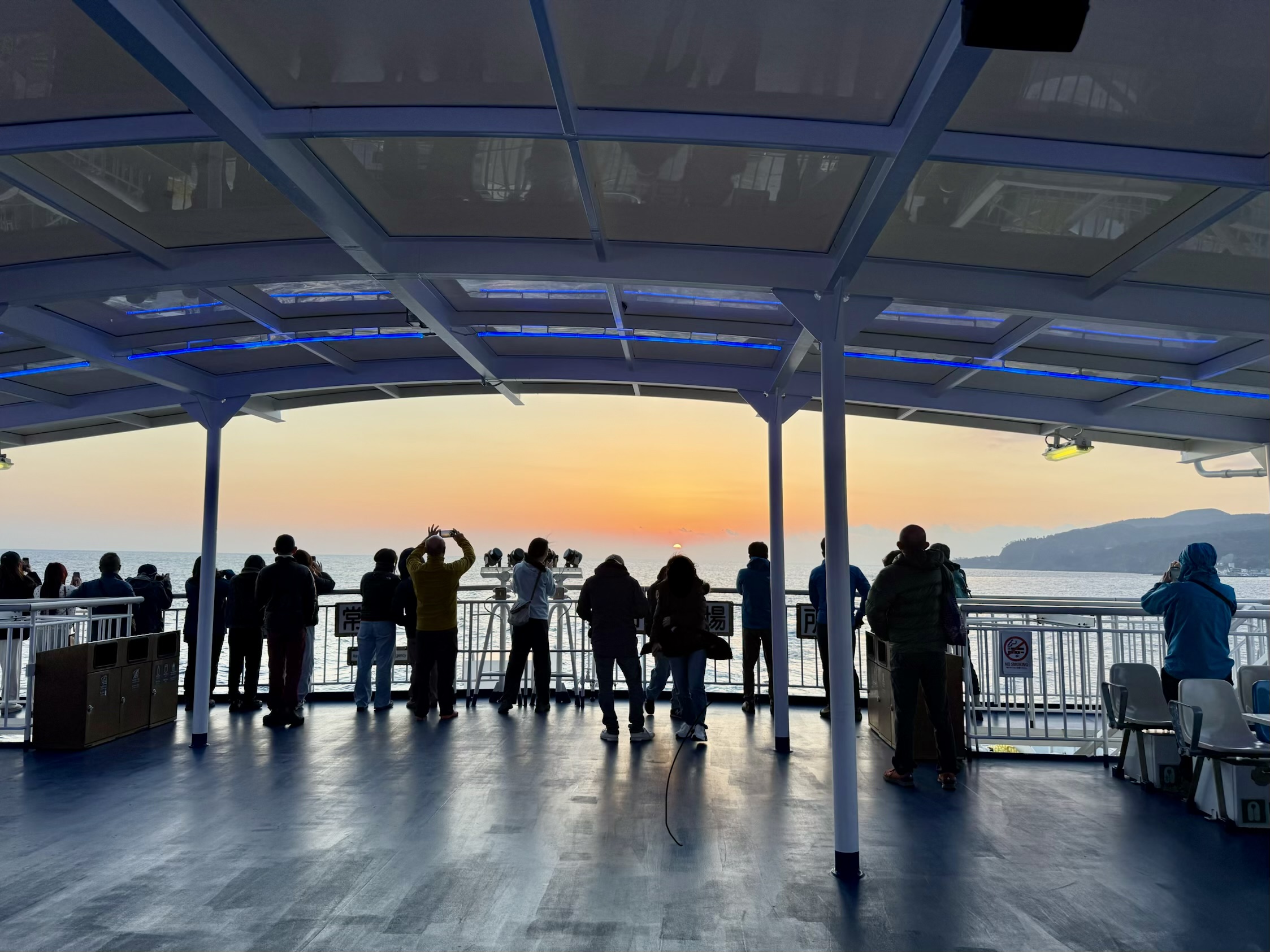 大型客船さるびあ丸で日の出を見る人々